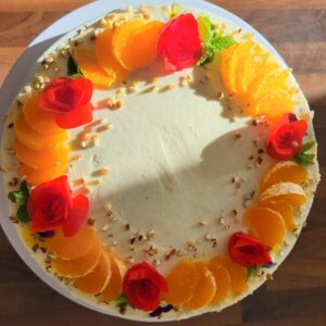ümmargune kohupiimatort, kaunistuseks apelsiinisektorid ja punased lilled