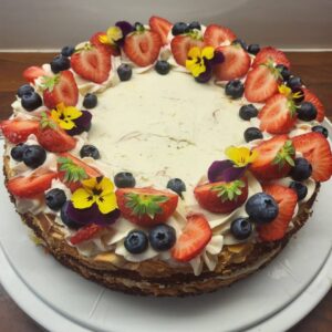 ümmargune, suvine maasikate, mustikate ja söödavate lilledega kaunistatud Brita kook