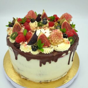 ümmargune vaarika- valge šokolaaditort. kaunistuseks viigimarjad, granaatõun ja kuldne toiduvärv