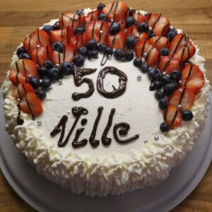 ümmargune kohupiima tort šokolaadist nime ja vanusega, kaunistatud maasikate ja mustikatega