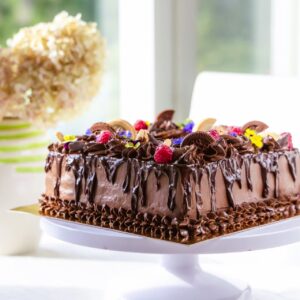 kandiline, rohke šokolaadi kaunistusega tort. kaunistuses šokolaadi lisaks küpsised, marjad, lilled ja mündlehed