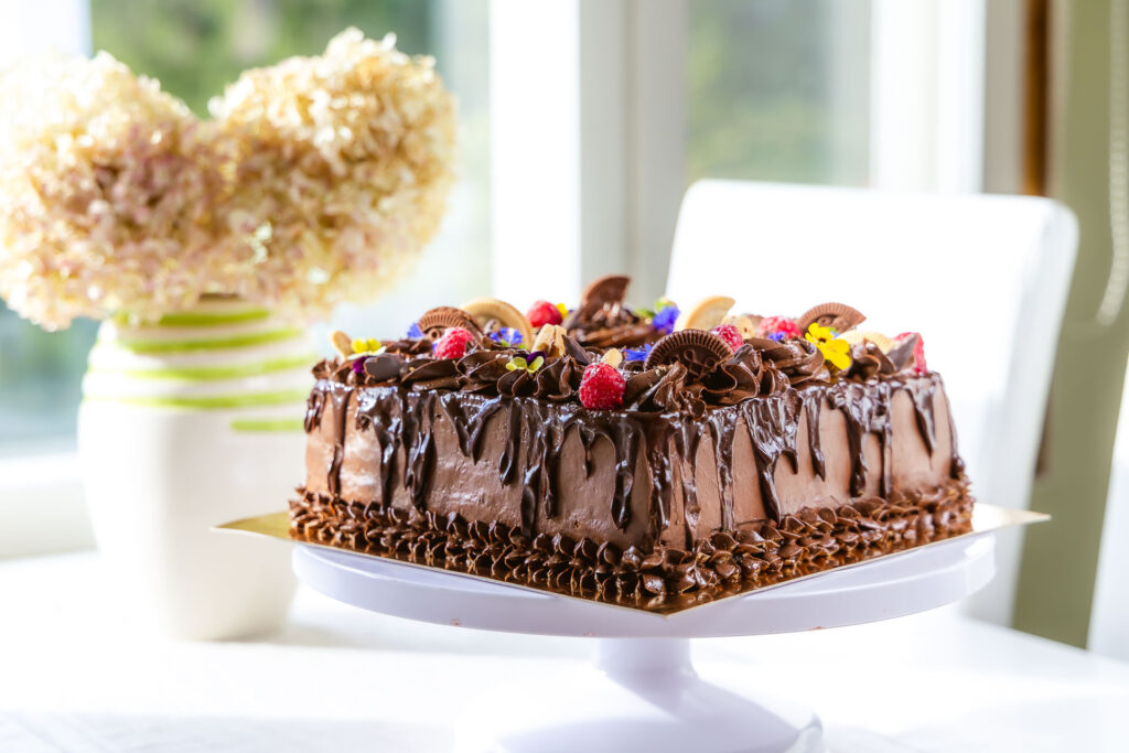 kandiline, rohke šokolaadi kaunistusega tort. kaunistuses šokolaadi lisaks küpsised, marjad, lilled ja mündlehed