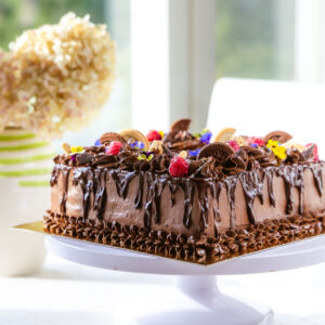 kandiline, rohke šokolaadi kaunistusega tort. kaunistuses šokolaadi lisaks küpsised, marjad, lilled ja mündlehed