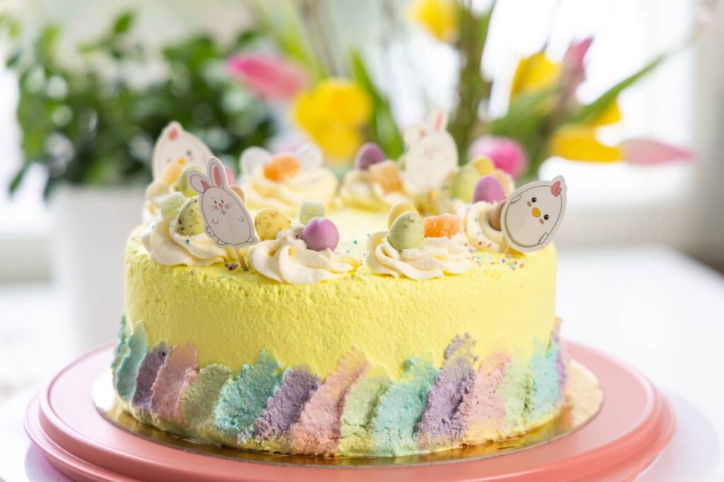 ümmargune, kollane lihavõtetort. kaunistus värviline kreem ja lihavõttemuna kommid, paberist tibud